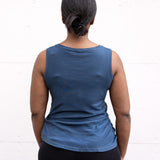 Woman standing facing backwards, wearing a full-length bamboo-organic cotton tank in slate blue, featuring a relaxed fit and rounded hem.