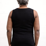 Woman standing facing backwards, wearing a full-length bamboo-organic cotton tank in black, featuring a relaxed fit and rounded hem.